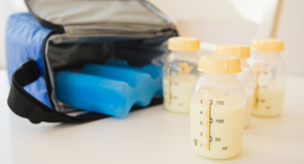 Bottles full of breast milk, with an ice pack and portable cooler in the background.