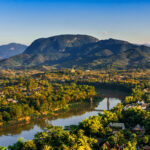 Sunset over Luang Prabang at the confluence of the Mekong and Nam Khan rivers, with hills in the distance