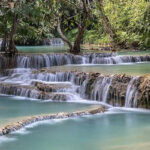 Kuang Si Waterfalls in Luang Prabang, Laos, with its emerald water pools. Perfect destination for nature lovers in August in Asia.
