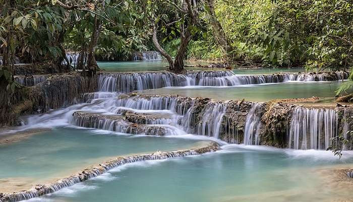 Kuang Si Waterfalls in Luang Prabang, Laos, with its emerald water pools. Perfect destination for nature lovers in August in Asia.